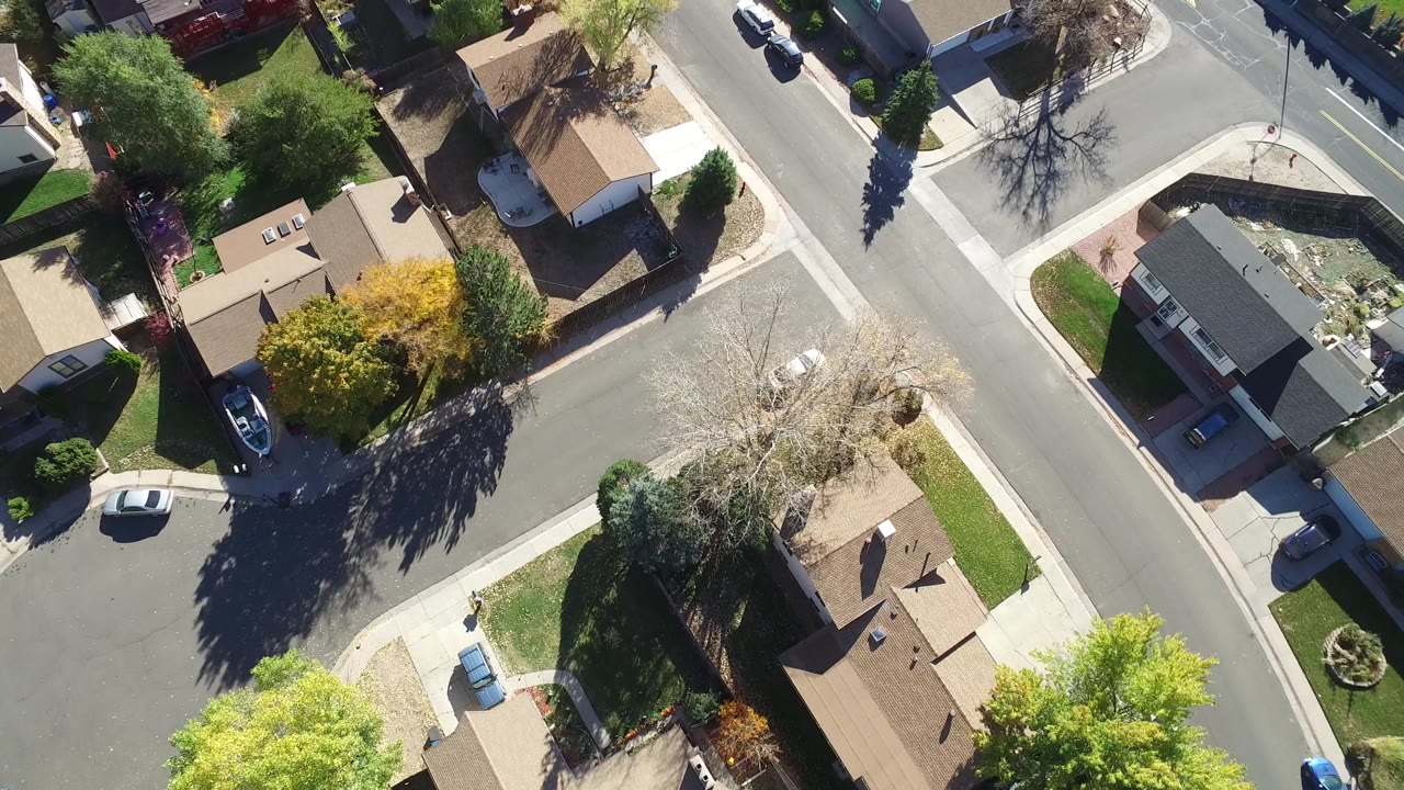 Second overhead frame in Hidden Lake, Colorado with diagonal residential roads, tan and gray rooftops, sidewalks, planted yards, parked vehicles, and no visible people.