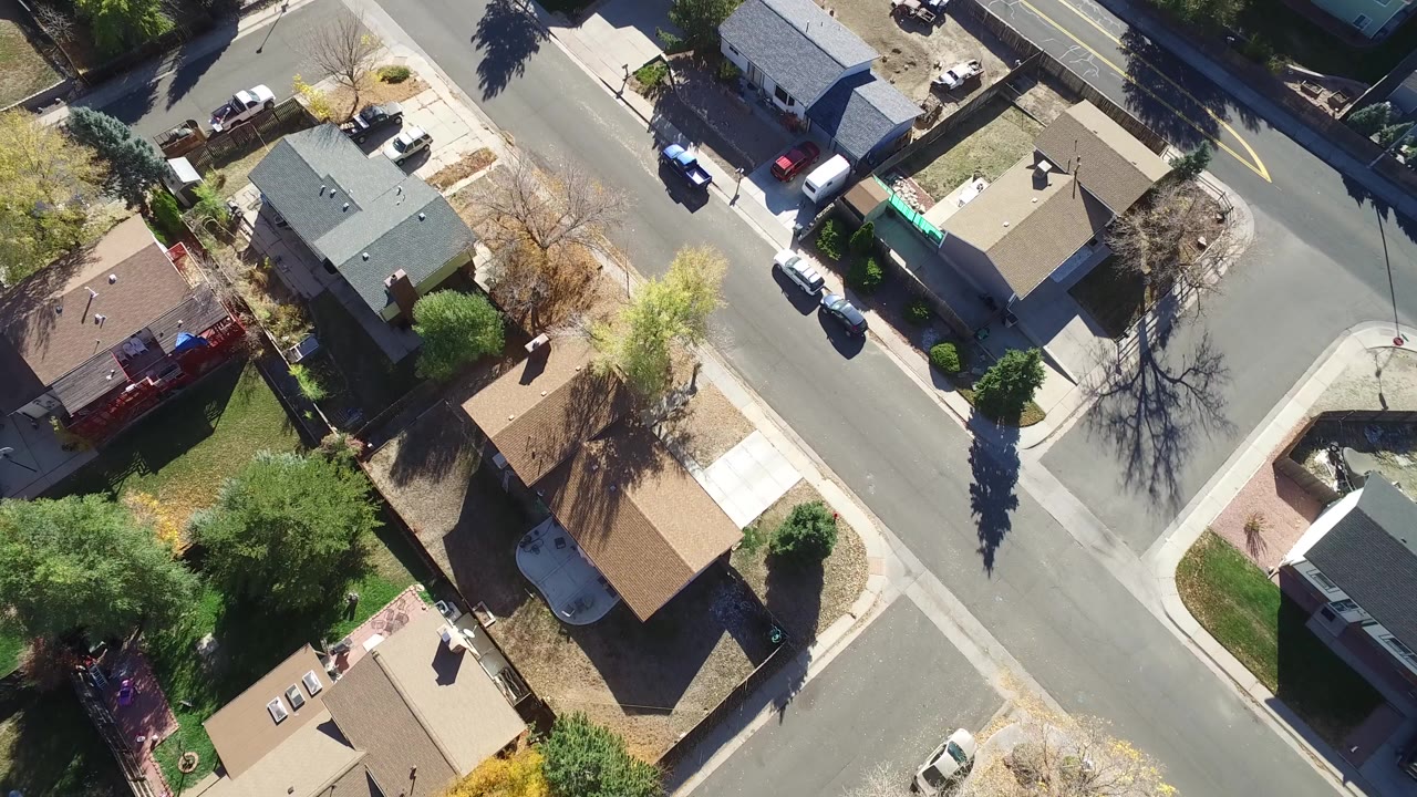Overhead view of houses, streets, cars, and trees in a residential neighborhood.