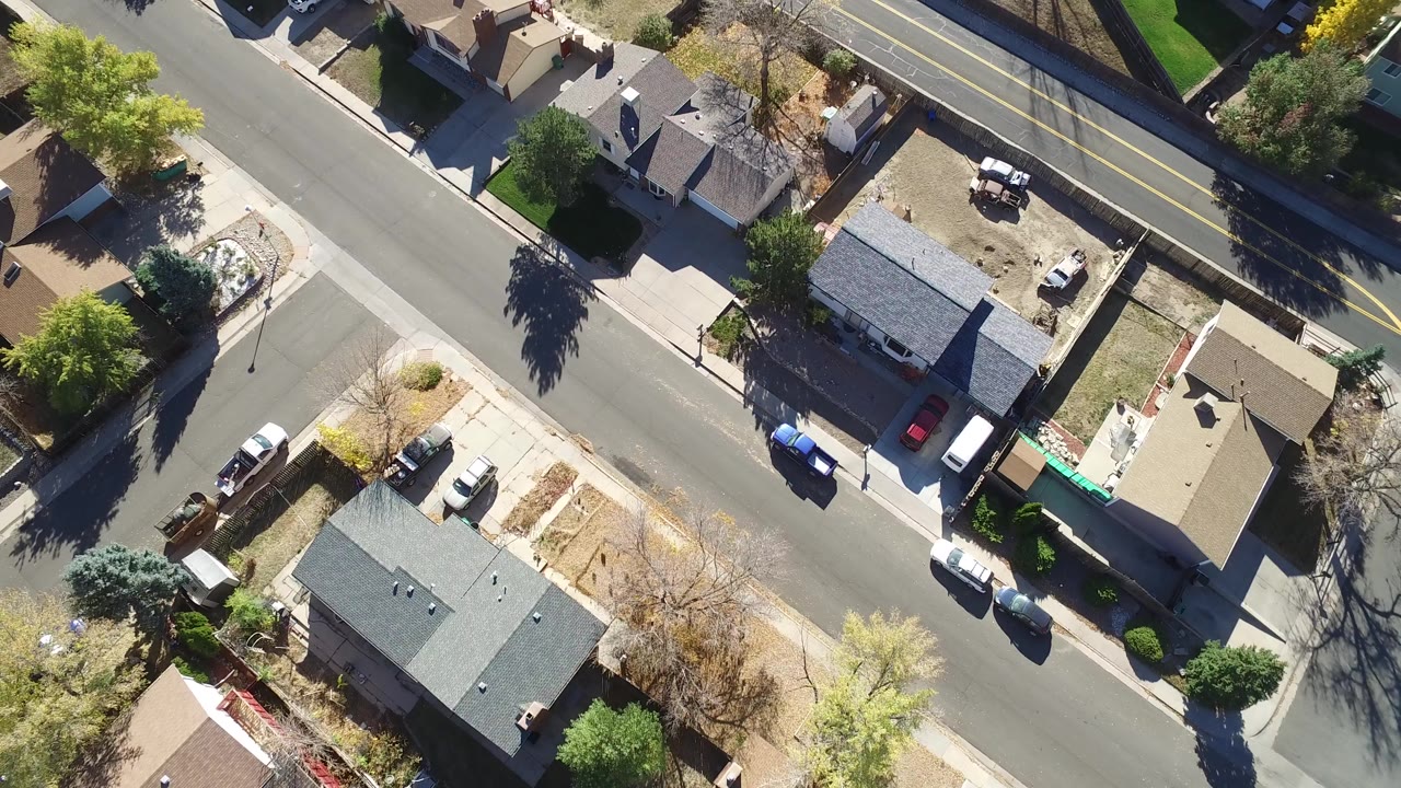 Overhead view of houses, streets, yards, and parked cars.