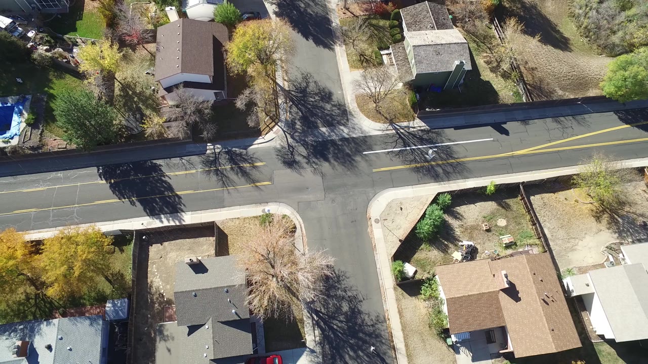 Top-down neighborhood street with houses, sidewalks, trees, and a bright blue tarp at the edge.