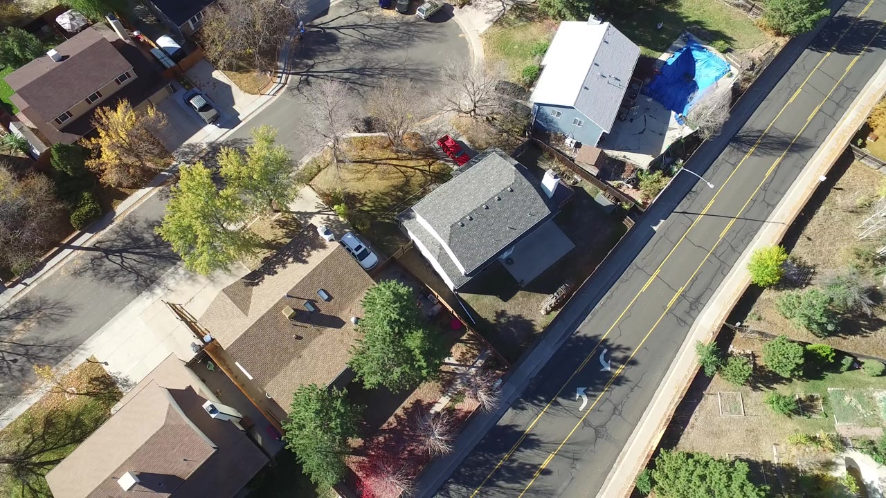 Overhead view of houses, trees, and a two-lane road.