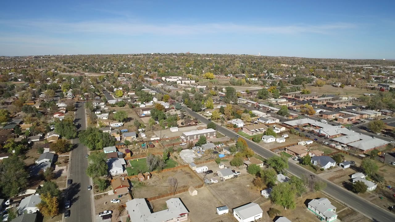 Opening aerial frame over Hidden Lake, Colorado, with rooftops, roads, brown lawns, scattered trees, and no visible people.
