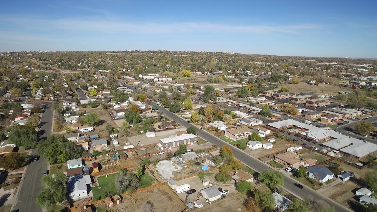 Second aerial frame over Hidden Lake, Colorado with a diagonal road, clustered homes, small lots, tree cover, and no visible people.