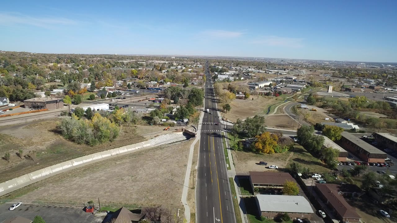 Aerial view of a divided road through low buildings and open lots.