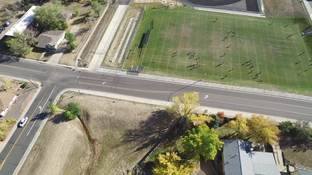 Overhead view of people on a grass football field beside a road.