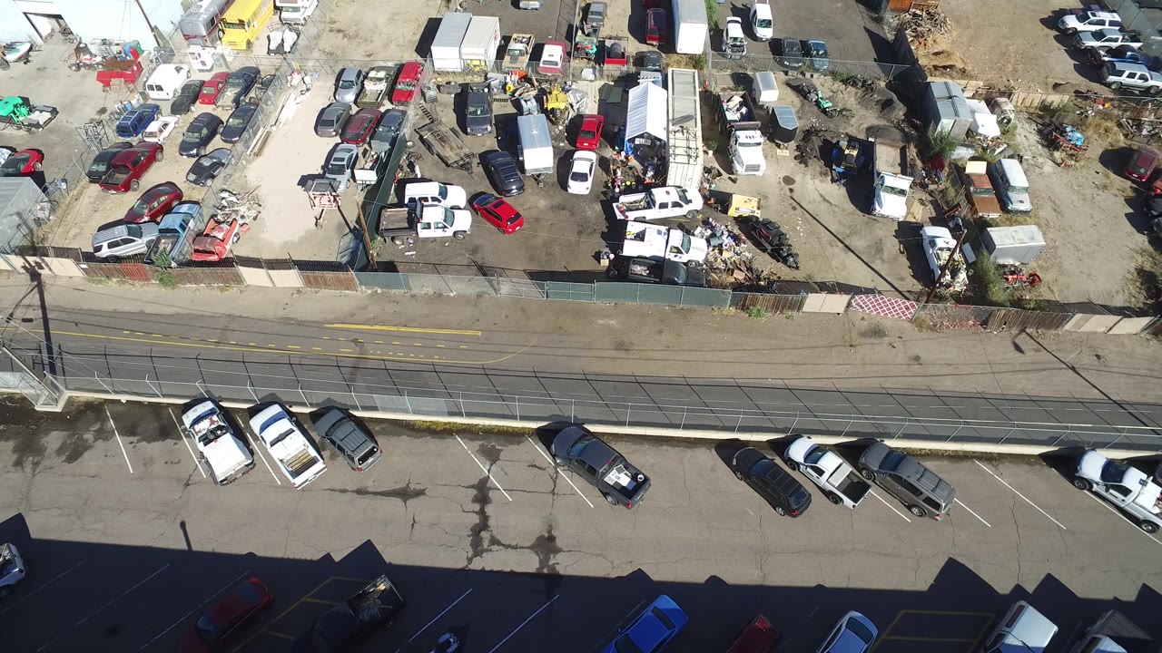 Drone view of a vehicle yard with a road and parking area below.