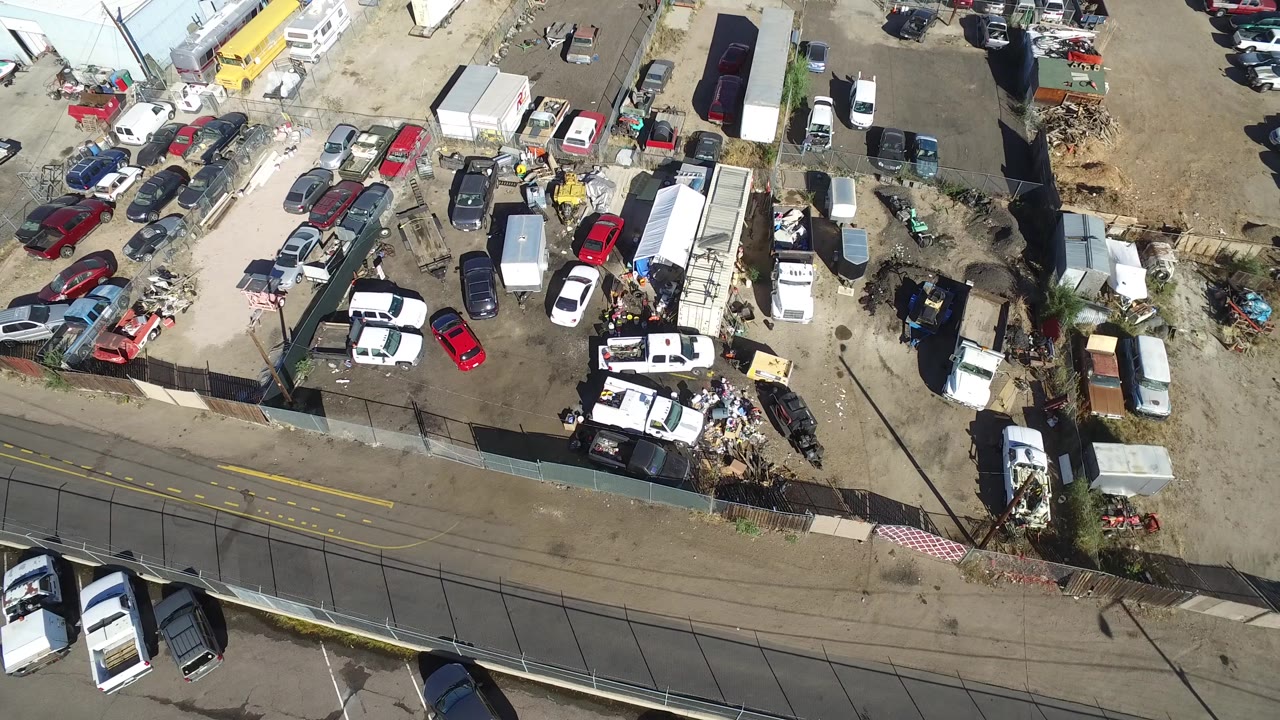 High aerial frame over Hidden Lake, Colorado showing rows of parked vehicles, white trailers, fenced yard areas, a roadside edge, and no visible people.
