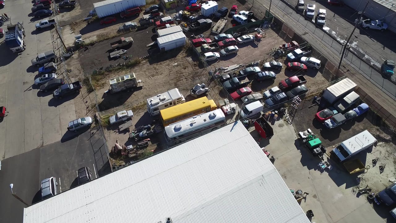 Overhead view of a white roof beside a fenced parking and storage lot.