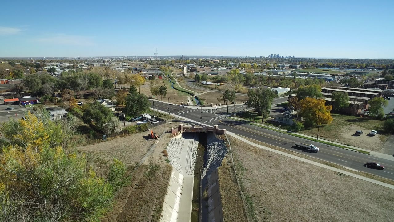 Aerial view of a suburban road intersection beside a concrete drainage channel.