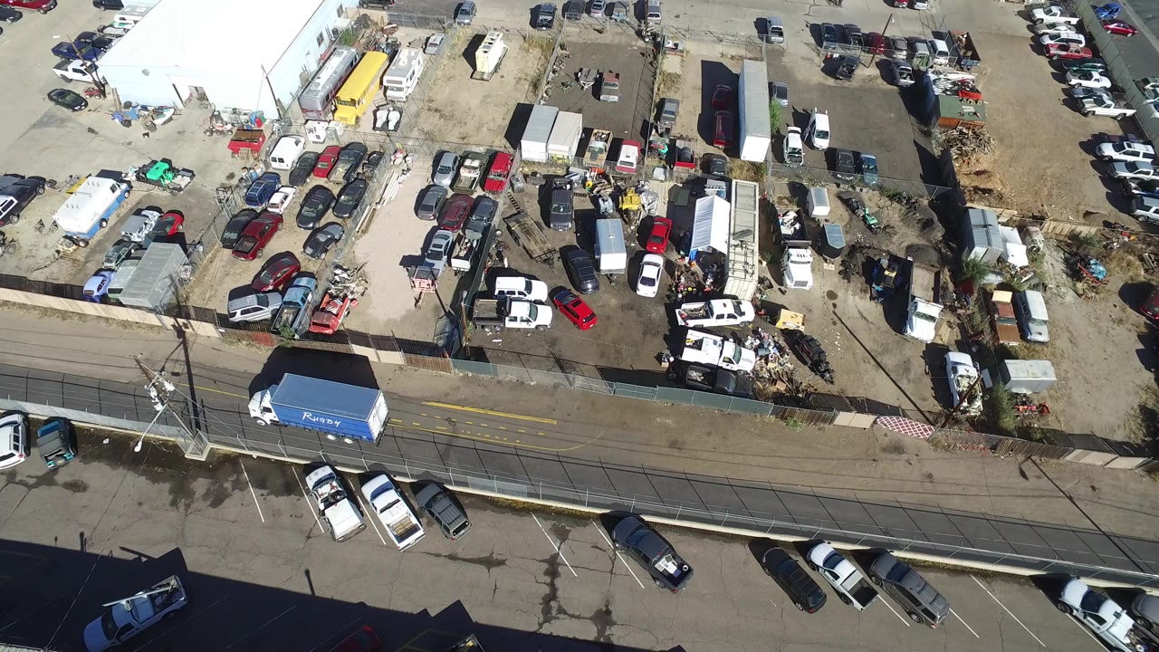 Overhead view of a crowded vehicle lot beside a road.