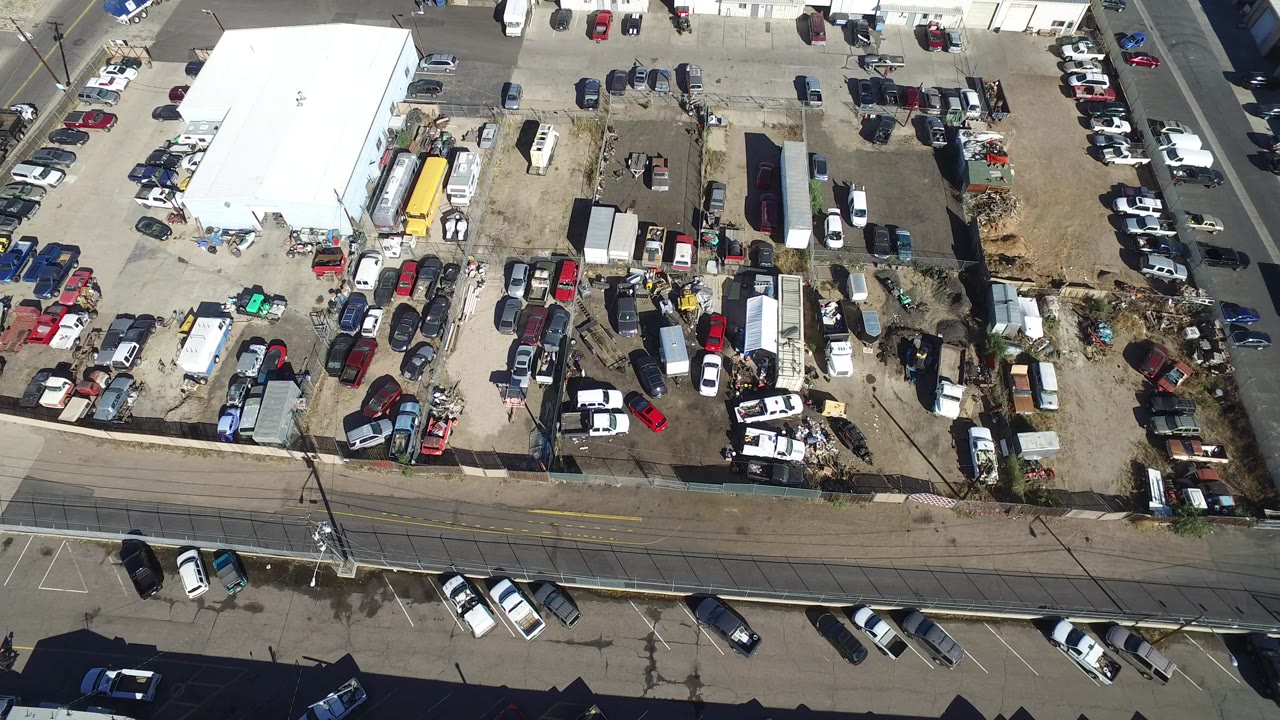 Overhead view of an industrial lot, parked cars, and an empty street.