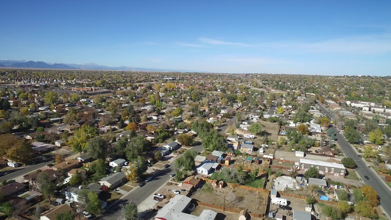 Hidden Lake, Colorado appears from a high aerial angle with a broad residential grid, small houses, mixed green and autumn-toned trees, and no discernible people.