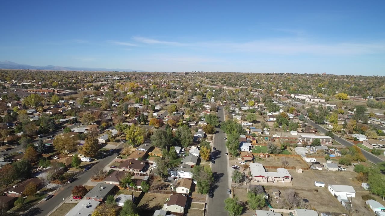 Second aerial frame over Hidden Lake, Colorado, showing more rooftops and residential blocks under clear daylight with no visible people.