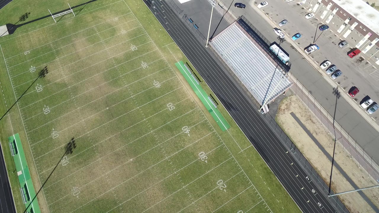 Aerial view of a football field beside a running track and bleachers.