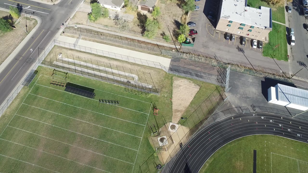 Overhead view of a marked field beside a running track and roads.