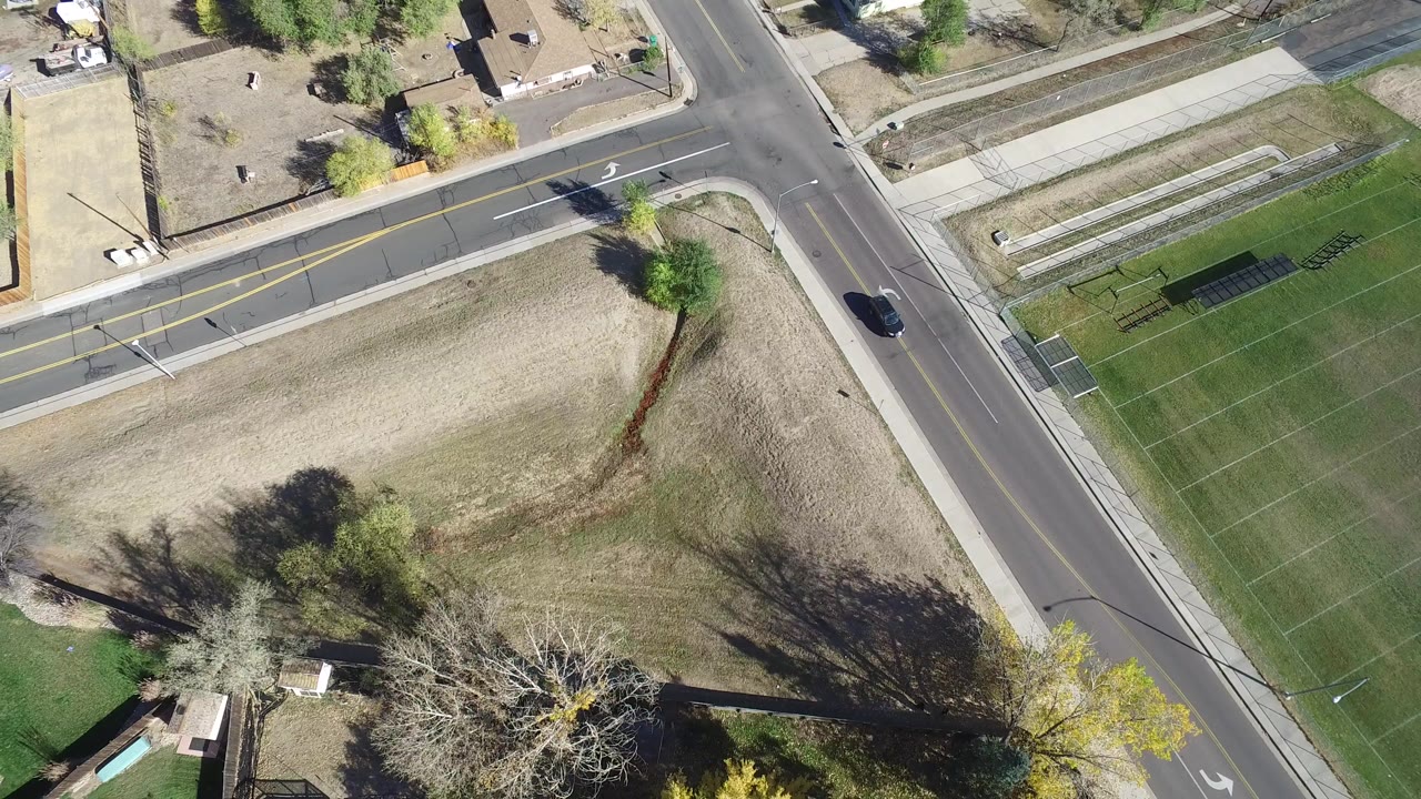 Overhead road and field with a car moving through the frame