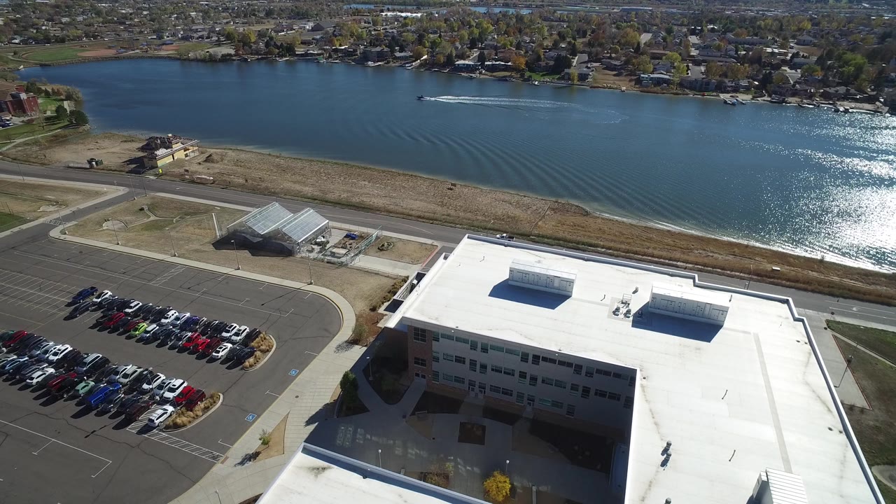 Drone-like overhead angle on a commercial roof, parking lot, and lake shoreline