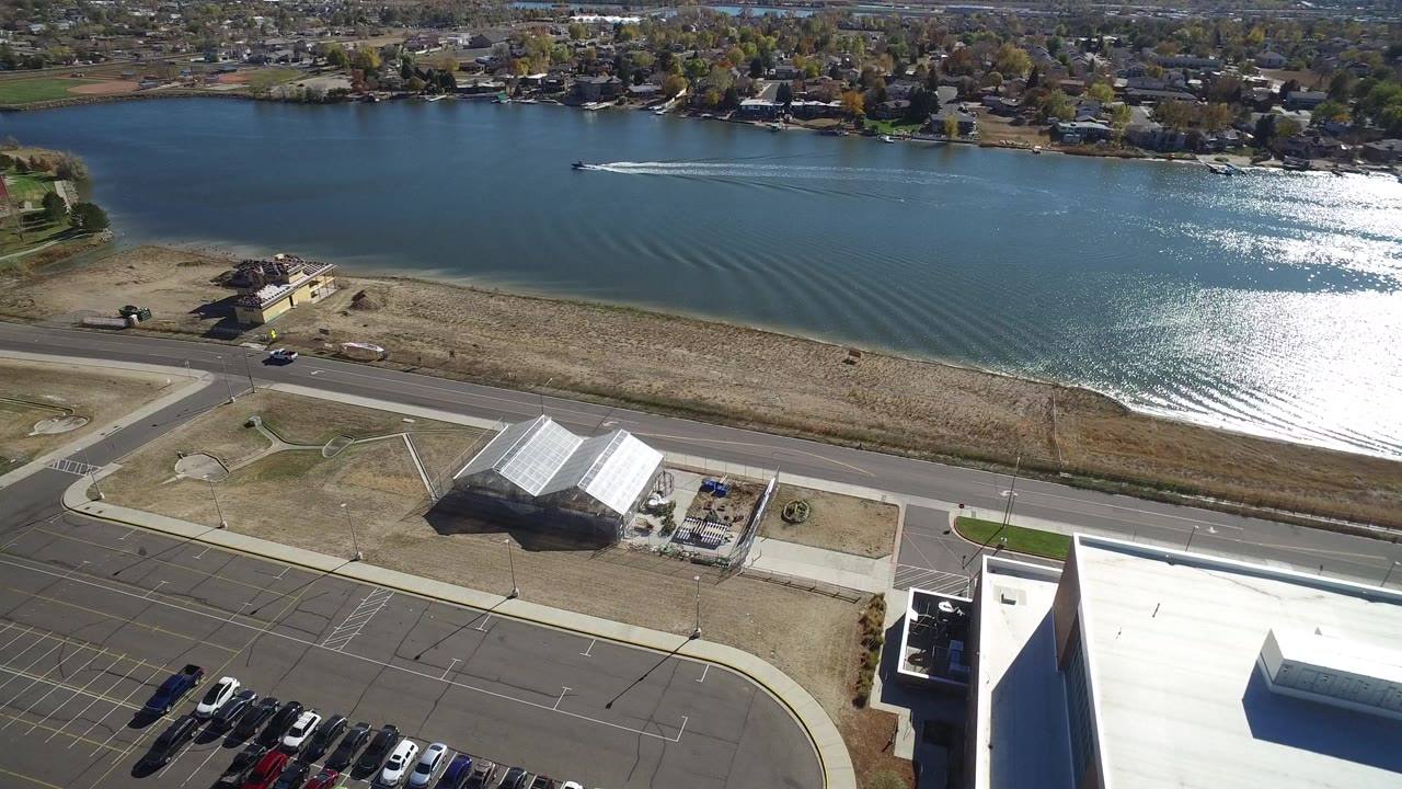 Aerial view of a speed boat on a lake beside roads and buildings.