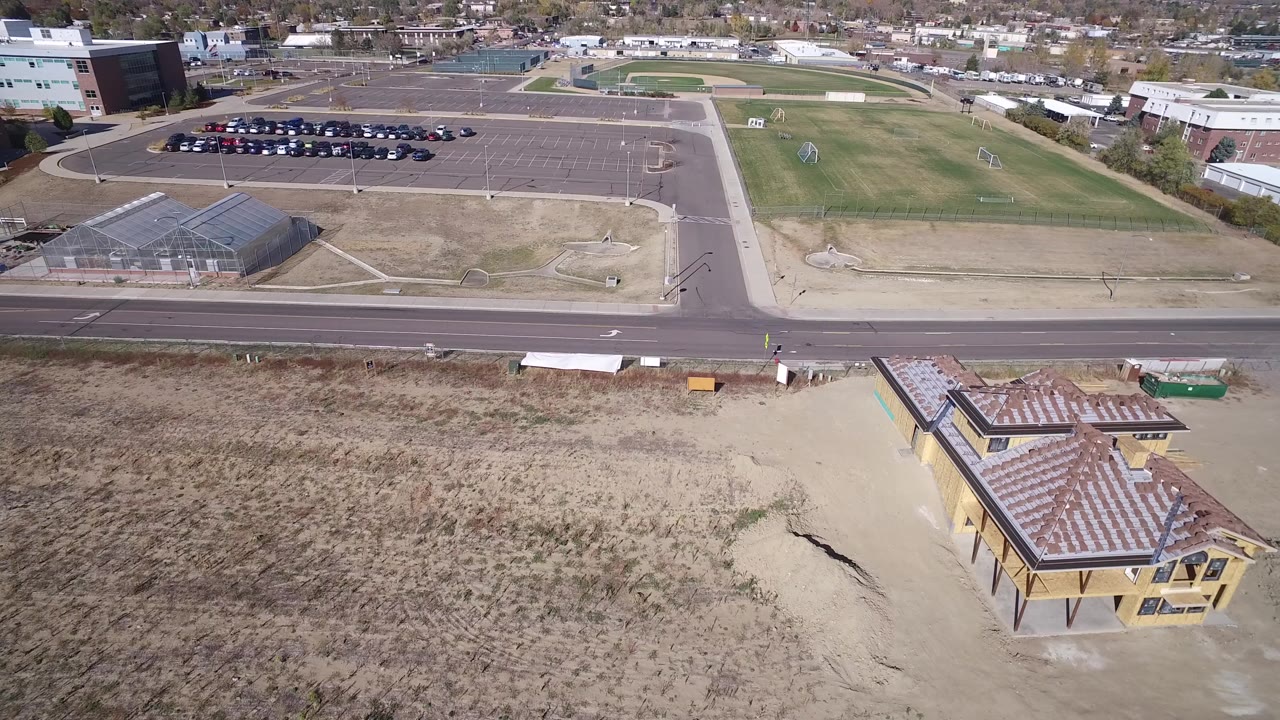 Aerial view over a road, parking lot, athletic field, and construction site.