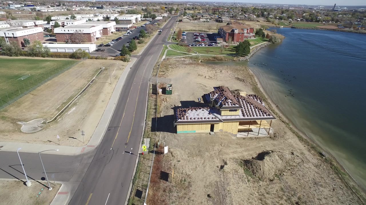 High aerial angle over a lakeside building, road, and open water.