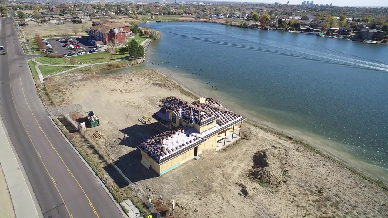 Aerial view of a lakeside building beside a road and blue water.