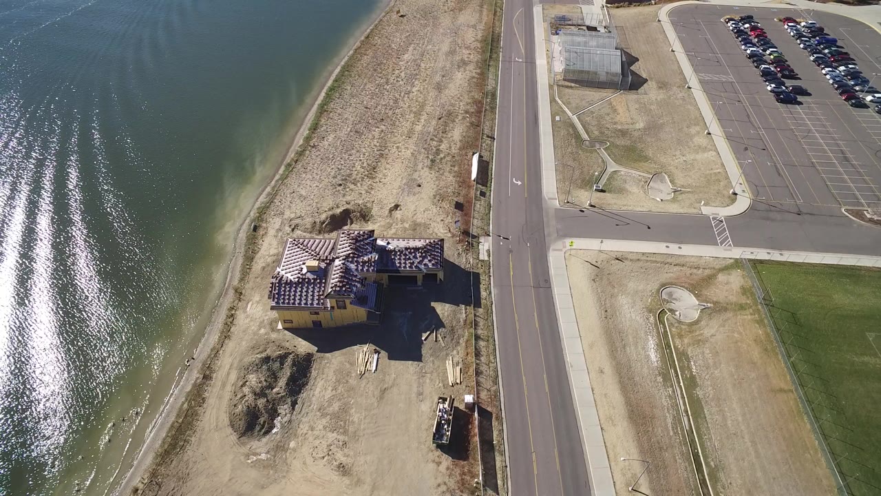 Aerial view of a damaged lakeside house beside a road and parking lot.
