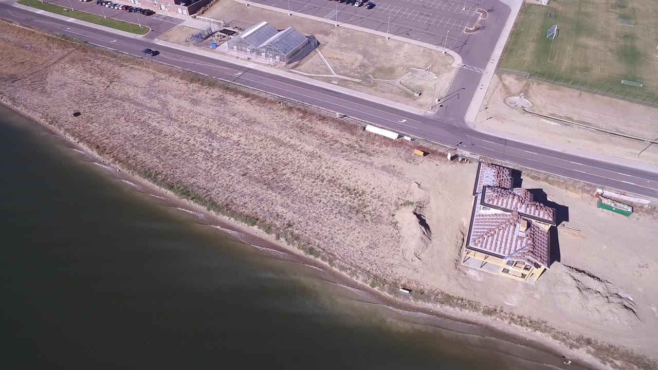 Aerial view of a road beside a lake shoreline and building complex.