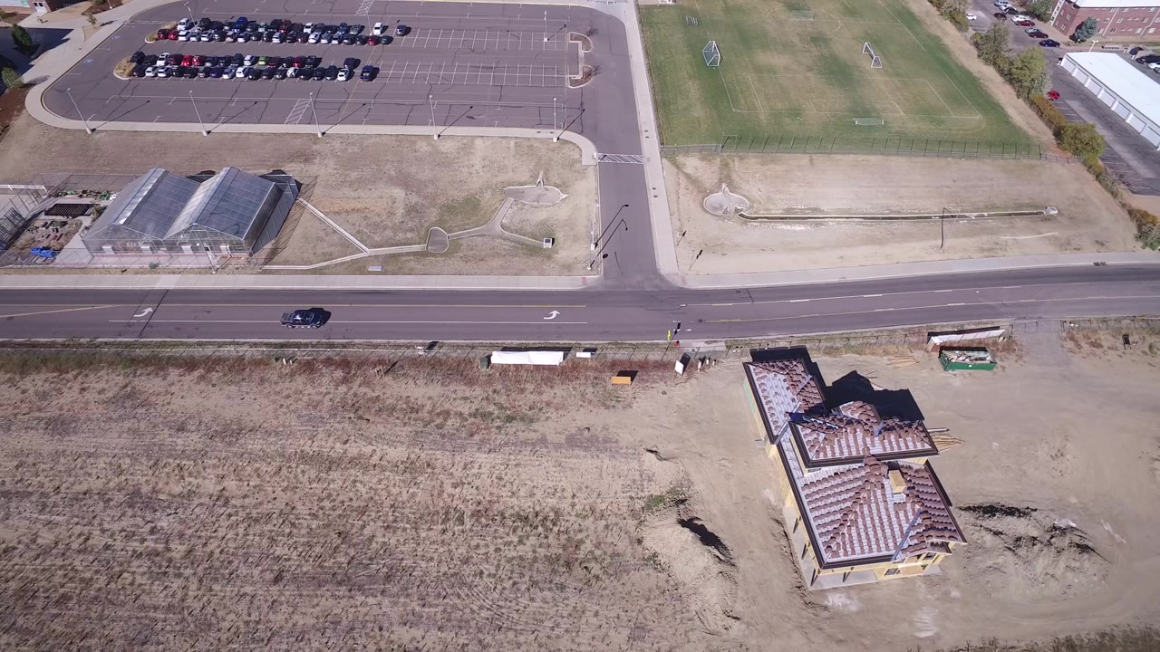 Aerial frame over Hidden Lake, Colorado with the road crossing the middle, parked cars at the top, dry lots below, and no visible people.