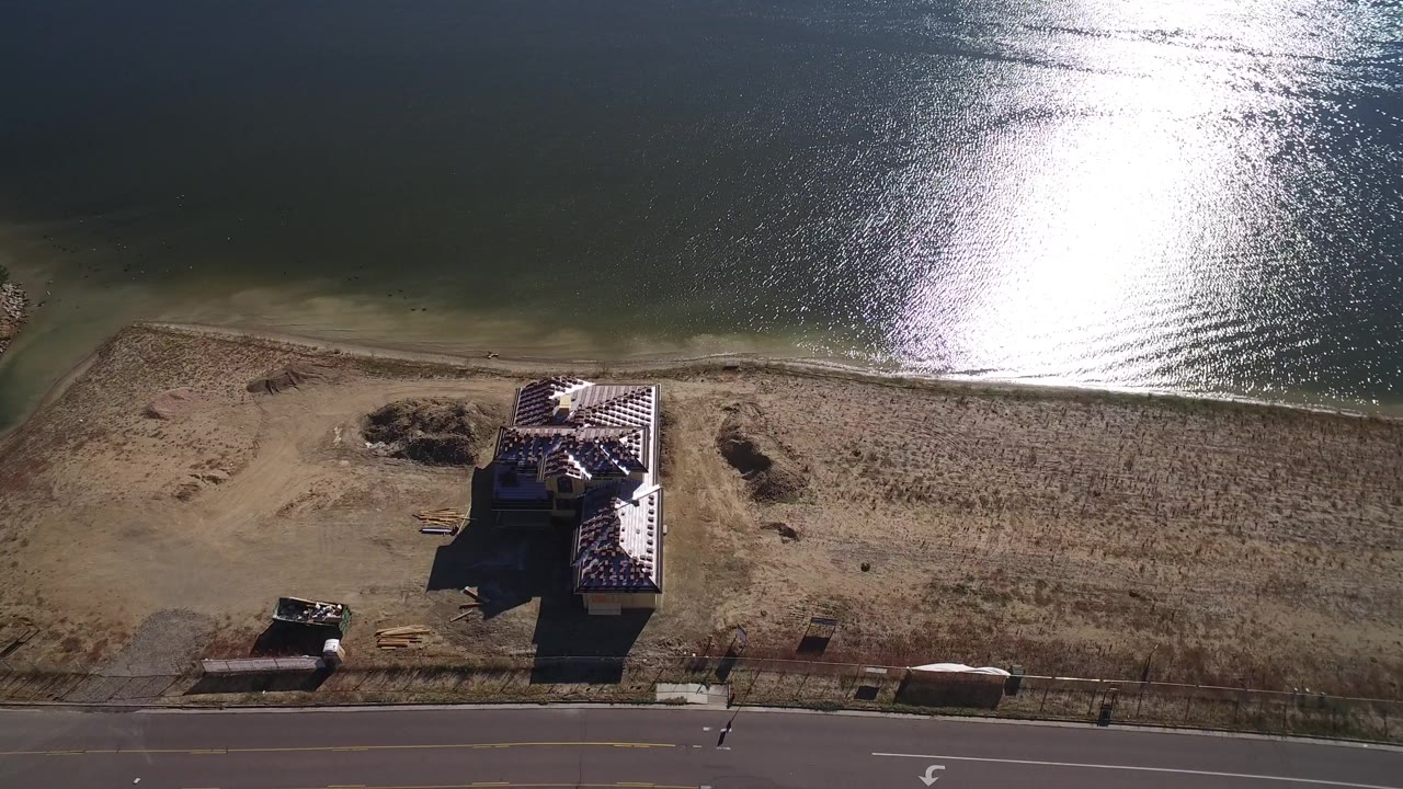 Drone-like overhead view of a house on a dry lakeshore near a road.