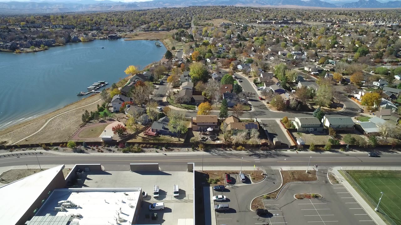 Aerial view of a lake beside a residential neighborhood and road.