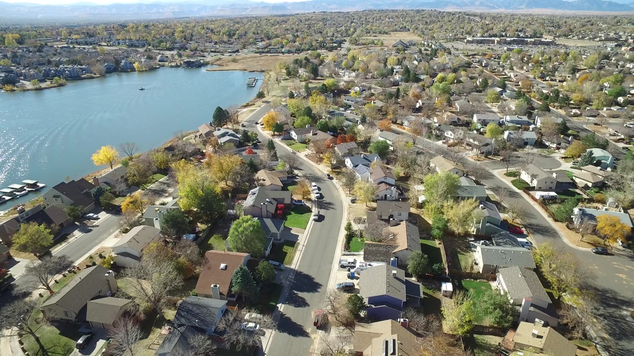 Aerial view of lakeside houses, curving streets, trees, and water.