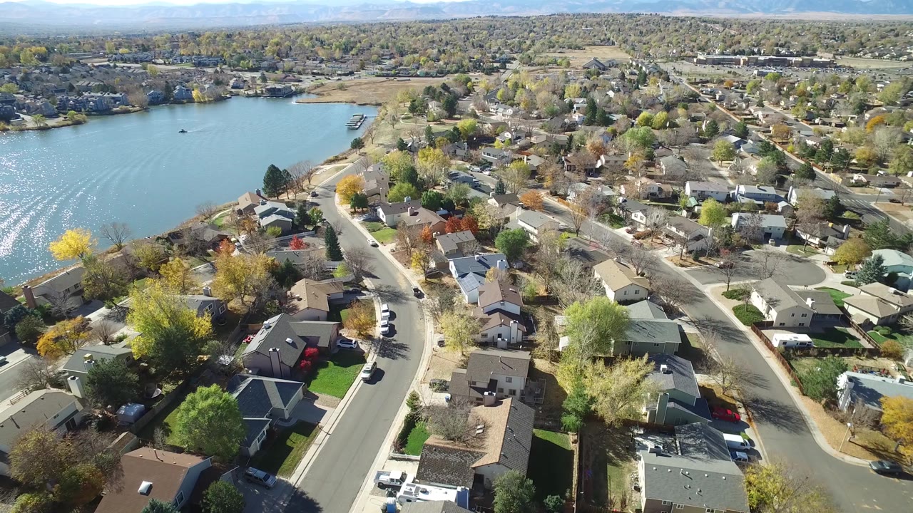 High view of suburban rooftops beside a lake in bright daylight.