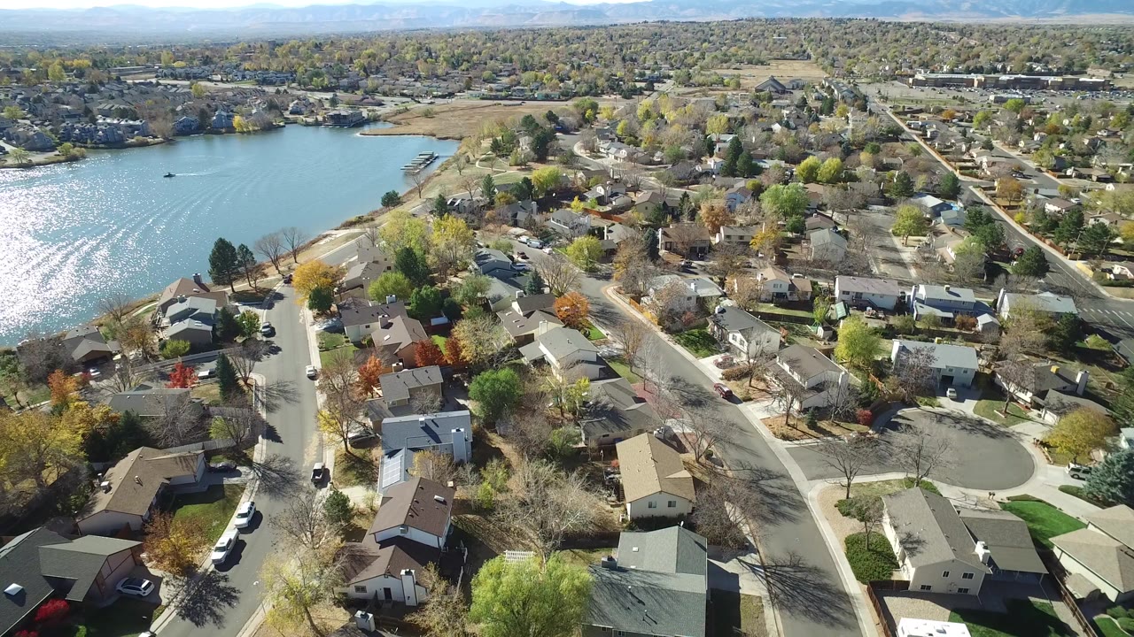 Aerial view of houses, streets, trees, and a bright lake.