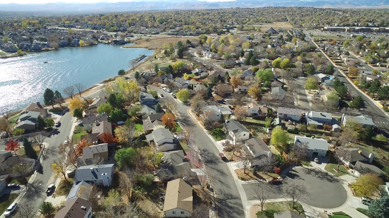 Aerial view of lakeside homes, streets, trees, and bright water glare.