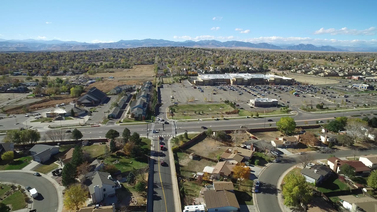 Aerial view of suburban roads, homes, parking lots, trees, and distant mountains