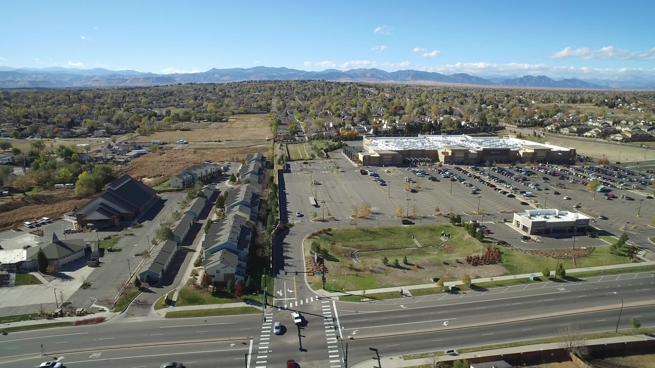 Aerial view of road intersection, townhomes, parking lot, and distant mountains