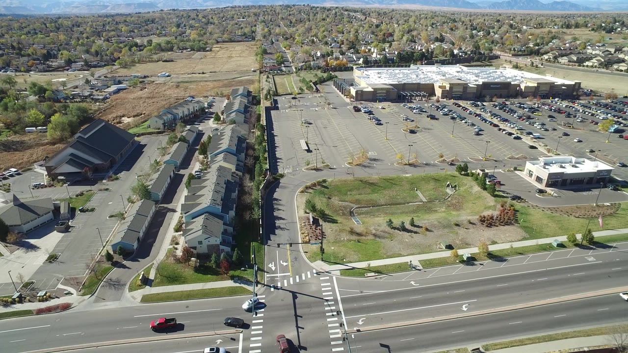 Aerial view of a suburban intersection beside townhomes and a large retail parking lot.