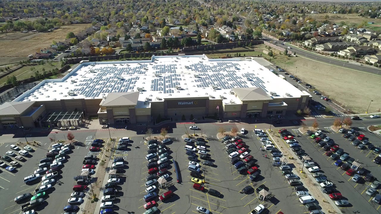 Aerial view of a crowded Walmart parking lot beside suburban homes.