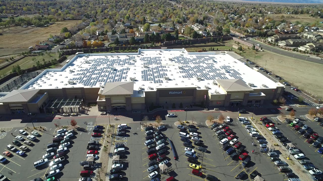 Aerial view of a Walmart store, parking lot, roads, and surrounding homes.