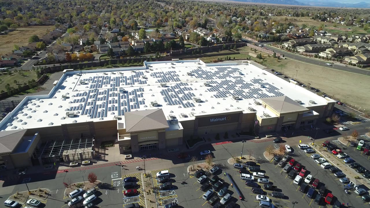 At 0:01, the Hidden Lake, Colorado aerial holds over the broad white roof, solar panel rows, front parking aisles, adjacent roads, and no visible people.