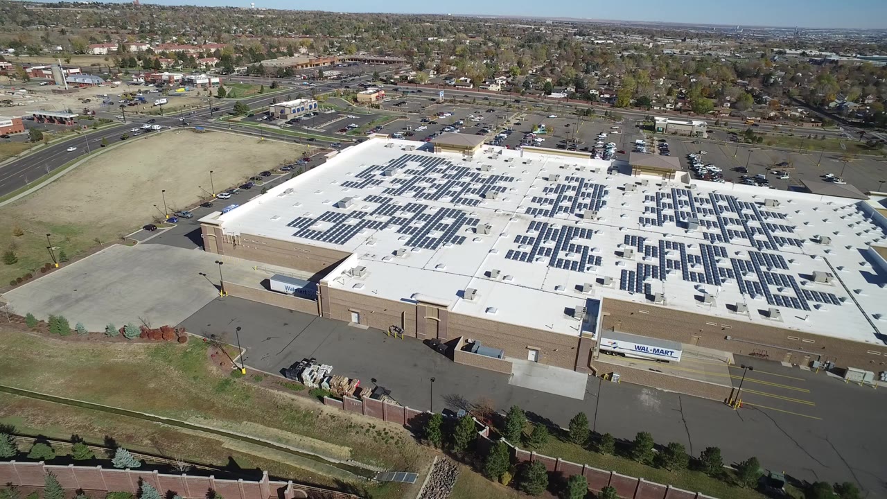 Aerial view of a large warehouse-style store with rooftop solar panels and rear pavement.