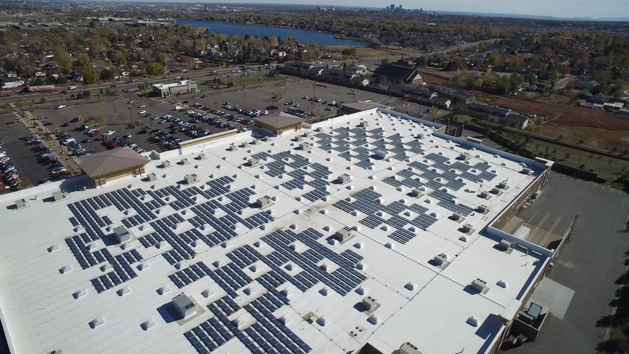 Aerial view of a white commercial roof covered with solar panels.