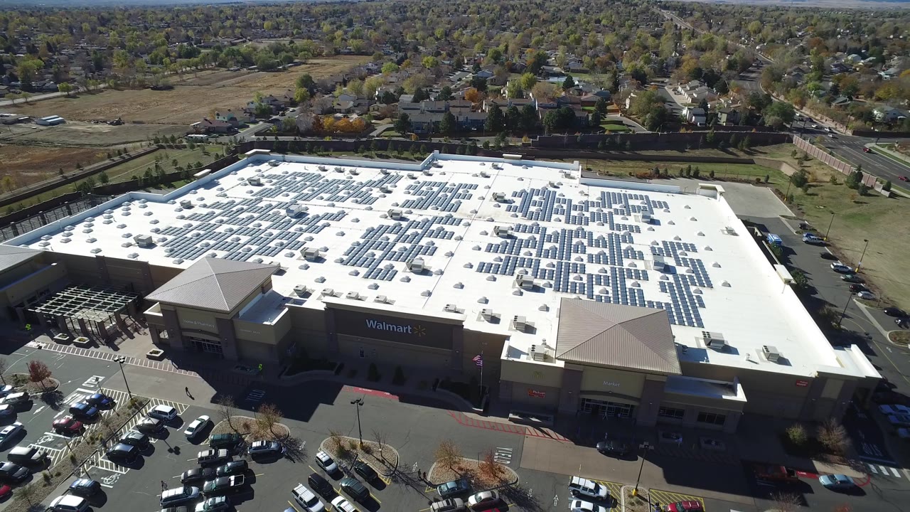 Large store roof with solar panels above a parking area.