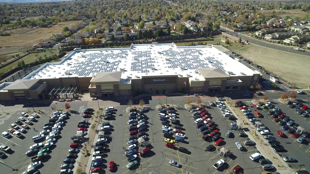 Drone view over Walmart roof, solar arrays, and suburban background.