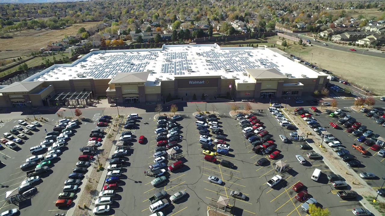 Elevated frame over a crowded parking lot in Hidden Lake, Colorado, with the Walmart sign centered on the storefront and no visible people.