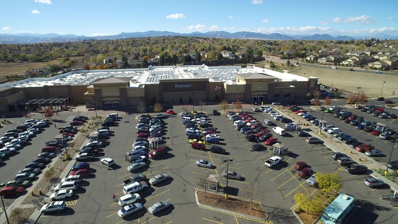 Aerial view of a Walmart store and full parking lot with mountains beyond.