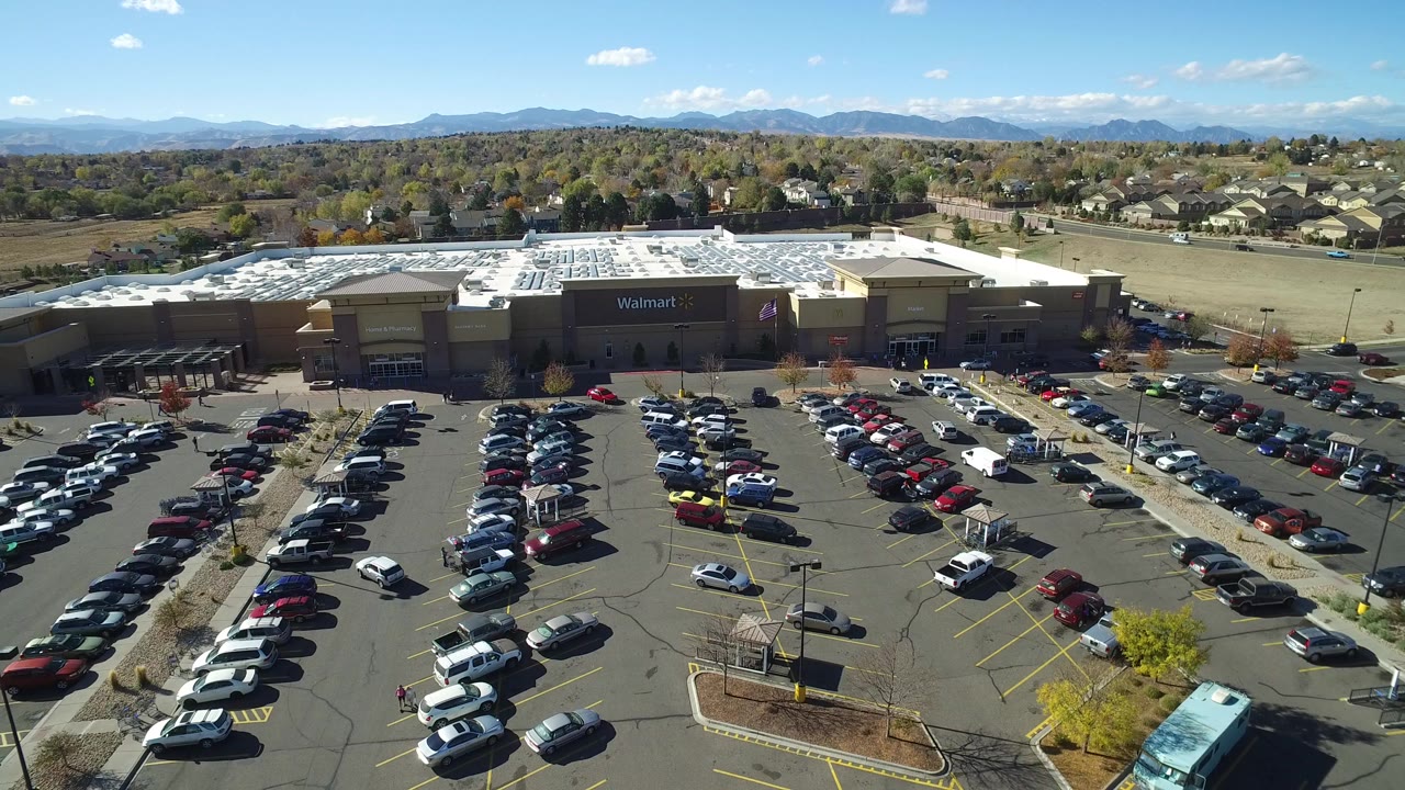 Oblique drone frame in Hidden Lake, Colorado with the Walmart building centered, packed parking rows below, residential streets behind, and no visible people.