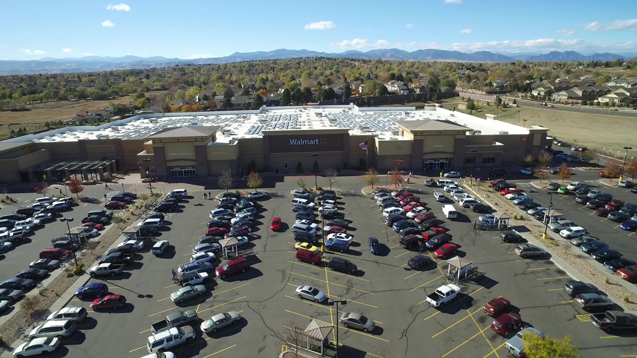 Aerial view of a Walmart parking lot with many cars and mountains beyond.