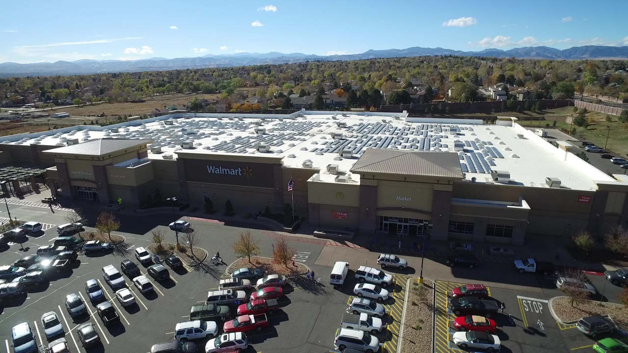 Aerial view of a Walmart store, parking lot, and distant mountains