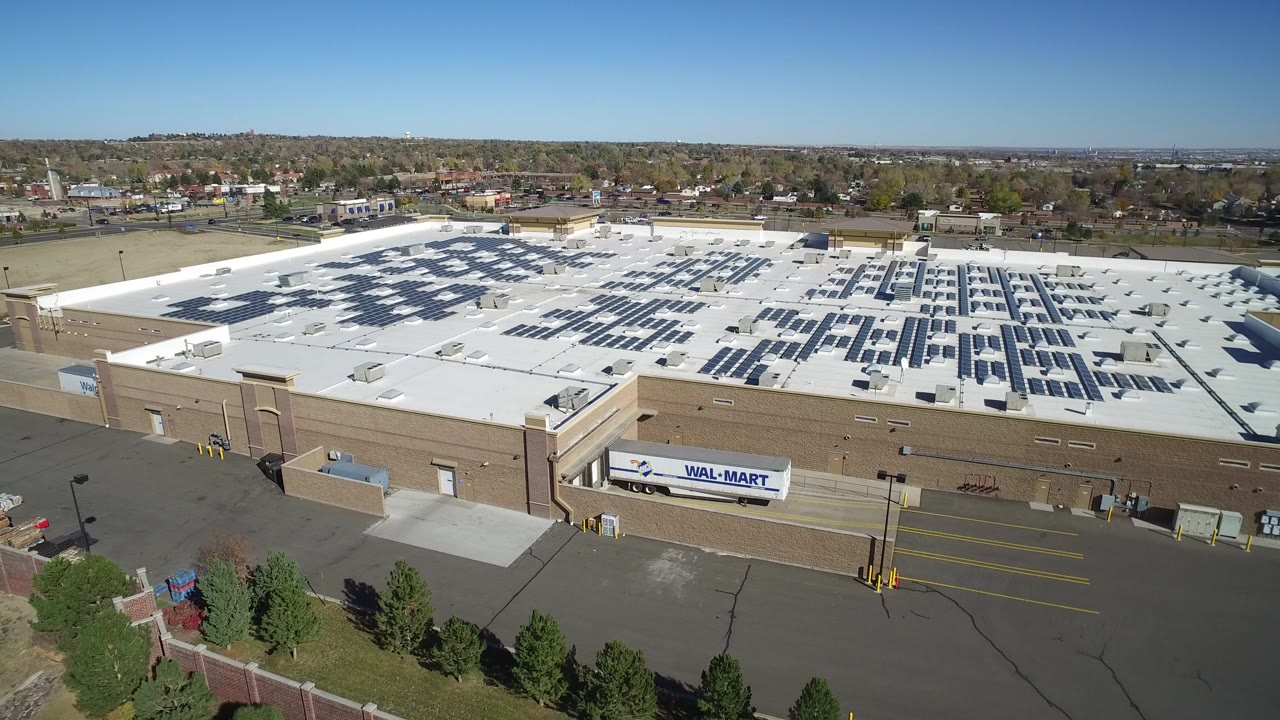 Aerial view of a large retail roof covered with solar panels.